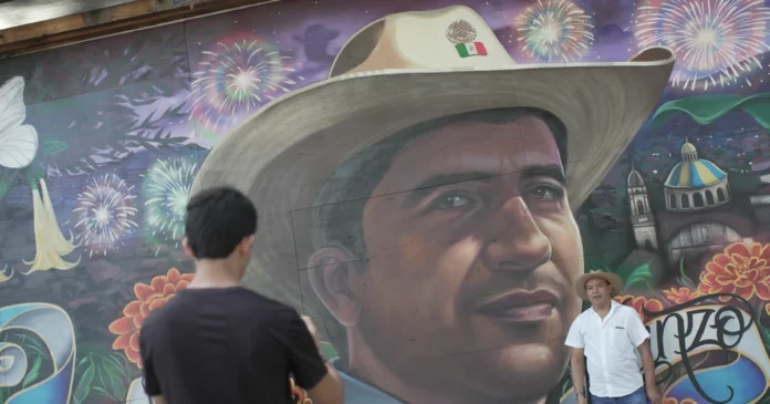 Una persona se toma una fotografía el viernes en el mural en memoria del alcalde de la localidad Carlos Manzo, realizado en el Parque Nacional de Uruapan, en el estado de Michoacán. Foto: EFE